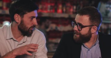 Londra İngiltere - 14 Nisan 2019: Barda otururken ofis kıyafeti giyen iki erkek arkadaşın görüntüsü. Yakışıklı iş adamları gayri resmi olarak bira fıçısıyla ilgili şeyleri tartışıyor..