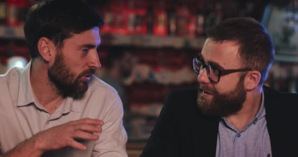 Londyn Wielka Brytania - 14 kwietnia 2019: Widok z bliska dwóch przyjaciół noszących ubrania biurowe komunikujących się siedząc w barze. Przystojni biznesmeni omawiający sprawy w nieformalnej sytuacji z poborowym piwem. — Wideo stockowe