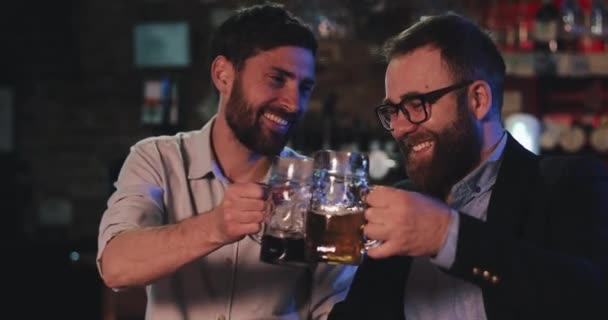 London UK - 14 april 2019: Lachende mannen die glaasjes drinken terwijl ze zich vermaken in de pub van dichtbij bekijken. Zorgeloze vrienden genietend van koud bier drinken en kletsen in de bar. Het begrip vrije tijd. — Stockvideo