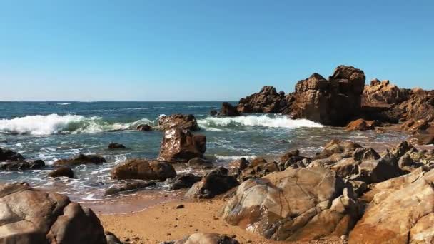 Дивовижний вид на пляж Марина з величезними каменями скель в денне світло. Морські хвилі розбиваються на скелястій береговій лінії з розпилювачем і піною. На скелястому березі океану. Повільний рух. Концепція морського пейзажу . — стокове відео
