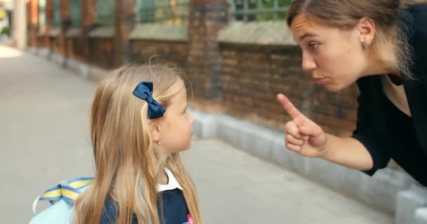 Sluiten van boze moeder schreeuwen op haar dochtertje op straat.Jonge vrouw op zoek streng terwijl gebaren en praten met haar 6-jarige kind in schooluniform. Begrip ouderschap. — Stockvideo