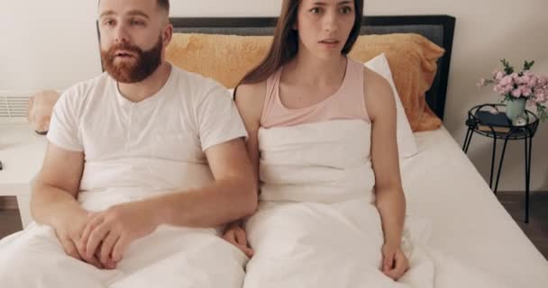 Retrato de jóvenes confundidos que se quedaron dormidos y sentados con grandes ojos. Pareja divertida despertando en pánico, gritando y que volver a caer en la cama.Concepto de estilo de vida y relación . — Vídeo de stock