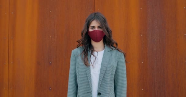 Recorte de vista de la mujer morena milenaria con máscara de algodón y mirando a la cámara. Retrato de chica atractiva joven con el pelo largo en mascarilla reutilizable. Concepto de prevención del virus . — Vídeos de Stock