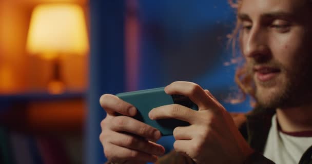 Close up view of excited young man playing game on his smartphone.Χαρούμενα χιλιετή hipster τύπος ψάχνει και συγκινητική οθόνη. Έννοια του παιχνιδιού και των συναισθημάτων.Θολή φόντο. — Αρχείο Βίντεο