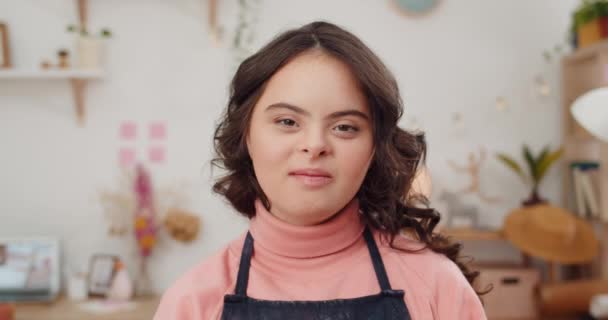 Close up view of charming teen girl with special needs looking to camera. Portrait of adorable sunny child with wavy brown hair posing in her room.Concept of people with down syndrome. — Stock Video