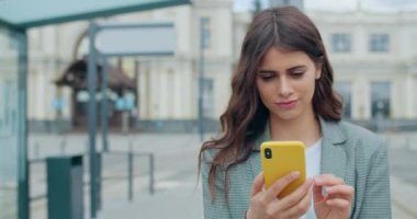 Şehir caddesinde odaklanmış, kayan ve telefon ekranına dokunan genç bir kadın var. Milenyum kızı gülümseyip yürürken akıllı telefonunu ve interneti kullanıyor. Açık havada..