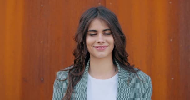 Vista de perto da menina muito feliz sorrindo e olhando para a câmera. Joyfull mulher milenar em roupas casuais posando para câmera. Conceito de emoções positivas. Fundo laranja . — Vídeo de Stock