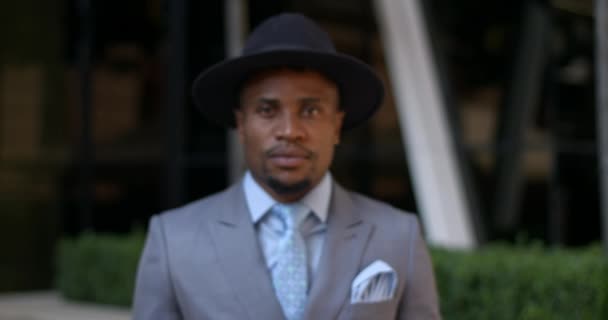 Felnőtt jóképű fickó, klasszikus öltönyben és nyakkendőben. Egy 30-as éveiben járó elegáns afro-amerikai üzletember portréja, aki kamerába néz, miközben az utcán áll. Közelíts rá!. — Stock videók