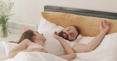 Güzel bir kadın yakışıklı kocasının karnında tatlı tatlı uyuyor. Sabahın erken saatlerinde yatakta yatan sevimli genç bir çiftin portresi. Aile ve ilişki kavramı.
