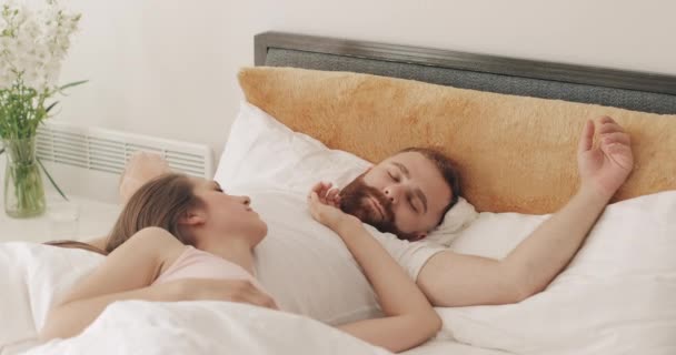 아름다운 여인 이 잘생긴 남편의 배 위에서 달콤하게 잠을 자고 있다. 이른 아침 침대에 누워 있는 귀여운 젊은 부부의 모습. 가족 과 관계에 대한 개념. — 비디오