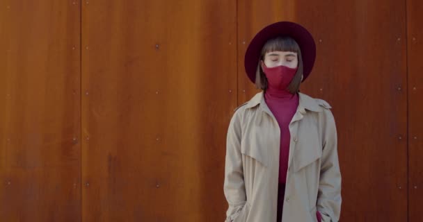 Vista de la cosecha de la mujer milenaria en la máscara de algodón protectora mirando a la cámara. Retrato de chica elegante cogida de la mano en los bolsillos y posing.Concepto de Covid 19 y pandemia de virus . — Vídeo de stock