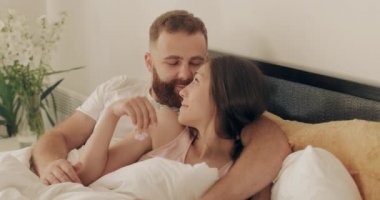 Romantik çift, sabahın erken saatlerinde yatakta yatarken sarılıp gülümsüyor. Aşık erkek ve kadın birlikte iyi vakit geçiriyorlar kucaklaşıyorlar ve gözlere bakıyorlar. Mutlu ilişki kavramı.