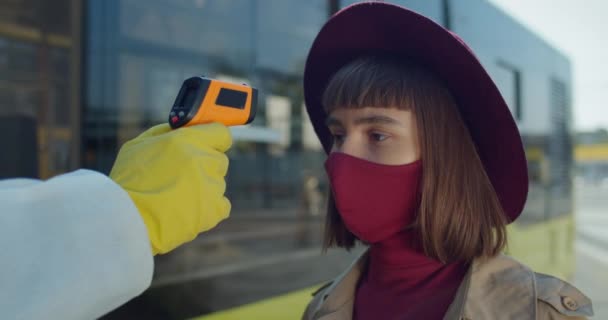 Close up shot of young female traveler having temperature checking before boarding bus. Concept of coronavirus protection and travelling. Outdoors. — Stock Video