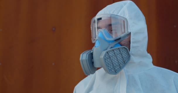 Portrét zdravotnického pracovníka v celkovém ochranném obleku a masce otáčející se hlavou a hledícího do kamery. Koncepce Covid -19, pandemie a ochrana proti virům. — Stock video