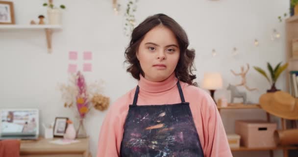 Adorable adolescente avec le syndrome du duvet regardant et posant à la caméra. Mignon enfant âgé portant dans les artistes tablier debout dans sa chambre. Concept d'enfants ensoleillés et ayant des besoins spéciaux . — Video