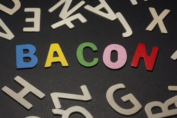 Bacon written with colorful wooden letters on a black background