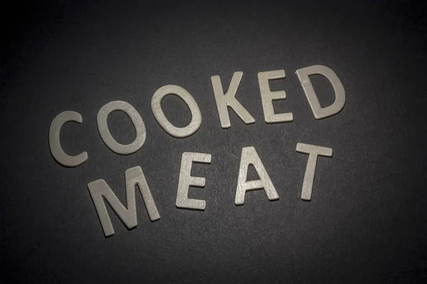 Μαγειρεμένο κρέας γραμμένο με ξύλινα γράμματα σε μαύρο φόντο — Φωτογραφία Αρχείου
