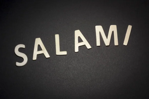 Salami écrit avec des lettres en bois sur un fond noir — Photo