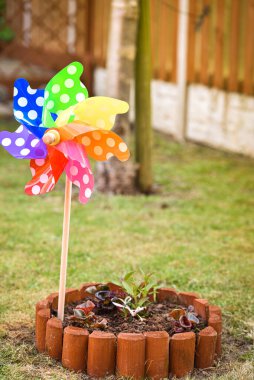 Dışarıdaki çocuksu renkli fırıldak görüntüsü. Güneşli bir yaz gününde yeşil çimenli bahçe.