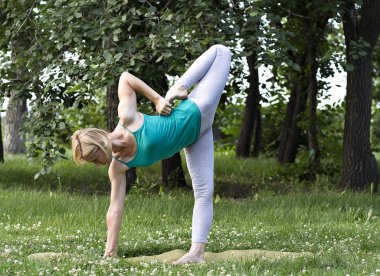 Genç sarışın kadının Yoga ve jimnastik park yapması