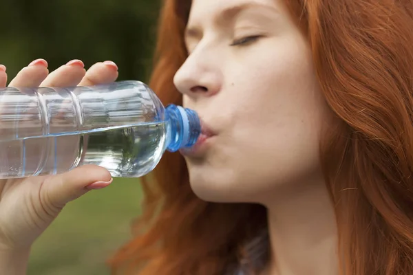 pure drinking water, young red-haired girl with a bottle of water, bottled water
