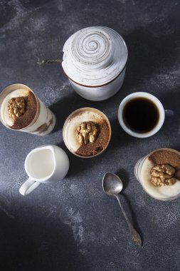 Tiramisu. Kremalı pandispanya. Koyu arkaplanda bir fincan kahve ve tiramisu..