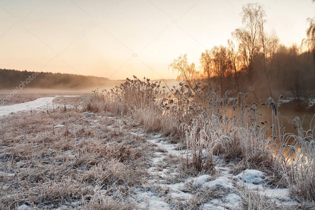 Winter misty dawn on the river. Rural foggy and frosty scene.