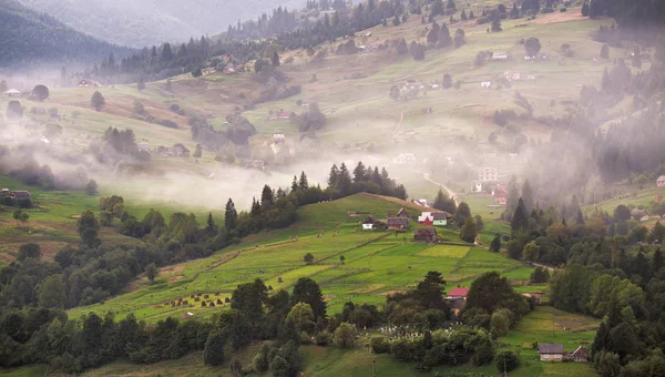 Alpské vesnice v horách. Kouř a opar nad kopci — Stock fotografie