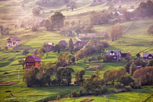 Alpino aldeia nas montanhas. Fumaça e neblina sobre colinas — Fotografia de Stock