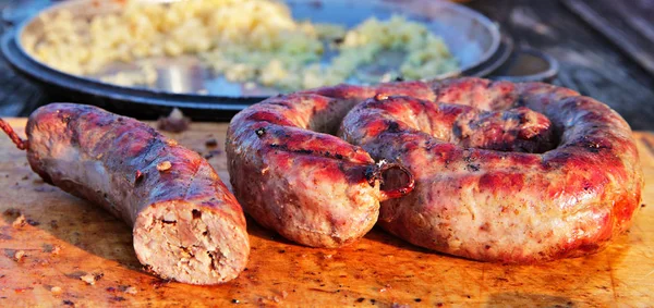 Délicieuses saucisses sur plaque de bois cuites sur barbecue — Photo