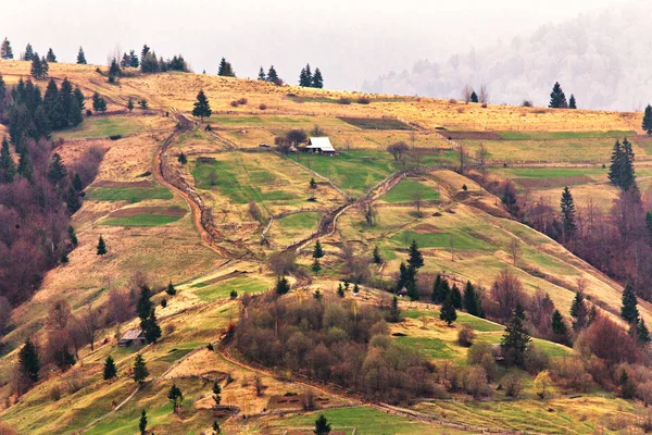 Pueblo de las montañas en las laderas. Colinas verdes en valle de montaña —  Fotos de Stock