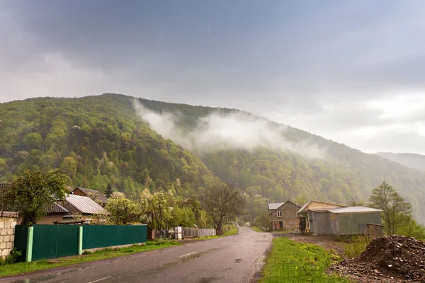 Frühling stürmisches Regenwetter. Straße und Dorf im grünen Gebirge — Stockfoto