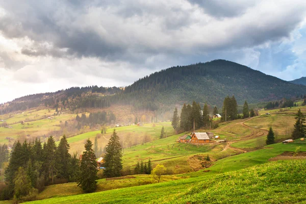 Green spring alpine scene. Mountain village on hillsides — Stock Photo, Image