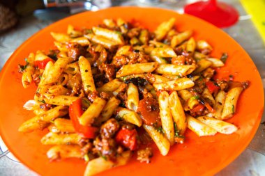 Portakal tabağında İtalyan usulü bolonez. Domatesli lezzetli İtalyan makarnası, taze fesleğen yaprağı ve rendelenmiş parmesan peyniri..