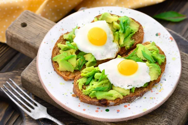 Avokado vaktelägg mackor i en platta på en trä bakgrund Stockfoto