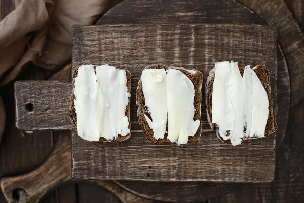 Sandwiches au pain de seigle noir au beurre sur une planche à découper en bois — Photo