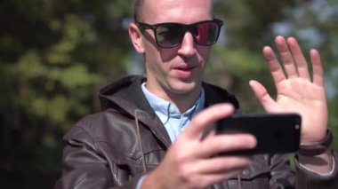 Mutlu bir çekici genç adam güneş gözlüğü kullanın video sohbet