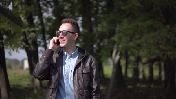 Молодой человек в солнечных очках разговаривает по телефону — стоковое видео