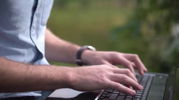 Молодой привлекательный мужчина работает за компьютером в парке — стоковое видео