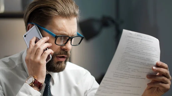 Affärsman tittar dokument talar telefon — Stockfoto