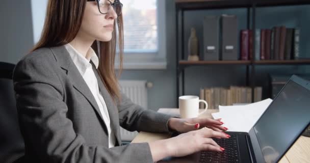 Tänksam kvinna i eyglass arbetar med dator — Stockvideo