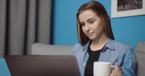 Sorrindo menina bebendo café e usando laptop em casa — Vídeo de Stock