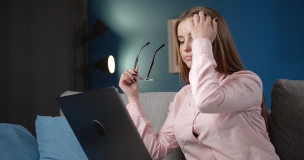 Tänksam dam som arbetar med bärbar dator i skyddsglasögon — Stockvideo