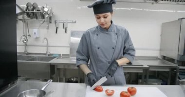 Üniformalı aşçı, domates kesiyor.