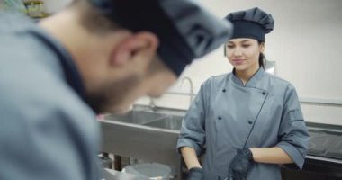 Restoranda ortağıyla yemek pişiren profesyonel kadın aşçı.