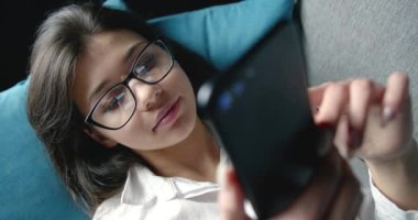 Akıllı telefon ekranının yansıması olan gözlüklü kadın.