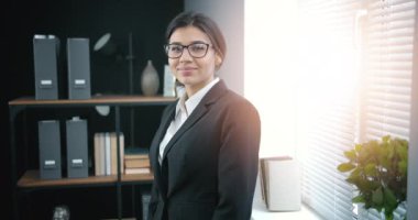 Modern ofiste koyu saçlı neşeli bir kadın.
