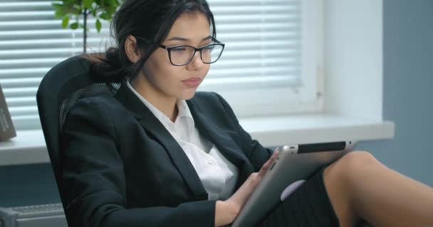 Mujer encantadora usando tableta mientras está sentado en la silla — Vídeos de Stock