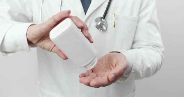 Médico masculino en uniforme vertiendo pastillas de la botella — Vídeos de Stock