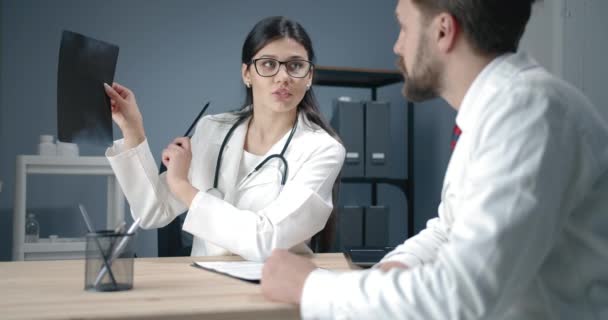 Médicos discutiendo rayos X en el consultorio — Vídeos de Stock